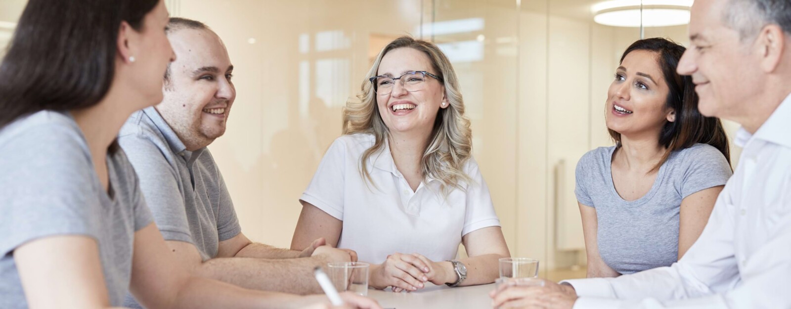 Mitarbeiter und Mitarbeiterinnen unterhalten sich lachend an einem Tisch.