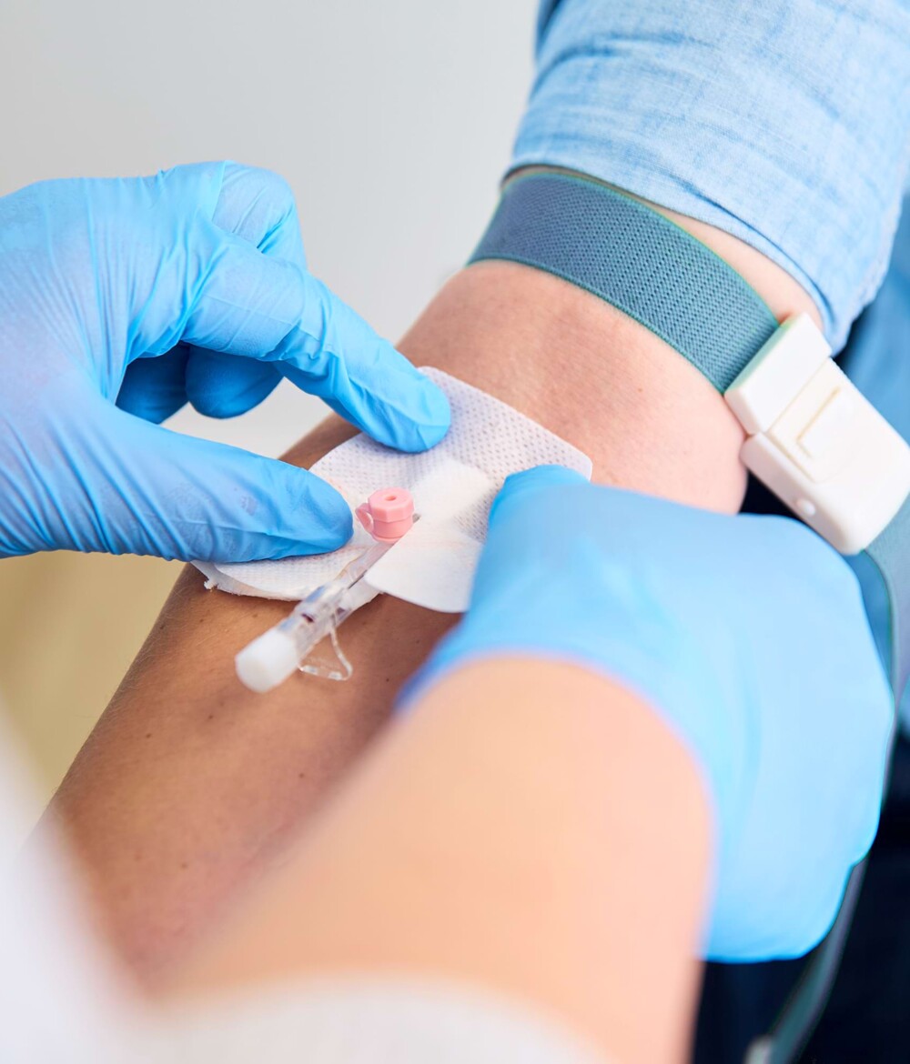 Nahaufnahme einer Armbeuge, w&auml;hrend eine Patientin einen Zugang f&uuml;r eine Vitamin-C-Kur von medizinischem Fachpersonal gelegt bekommt.