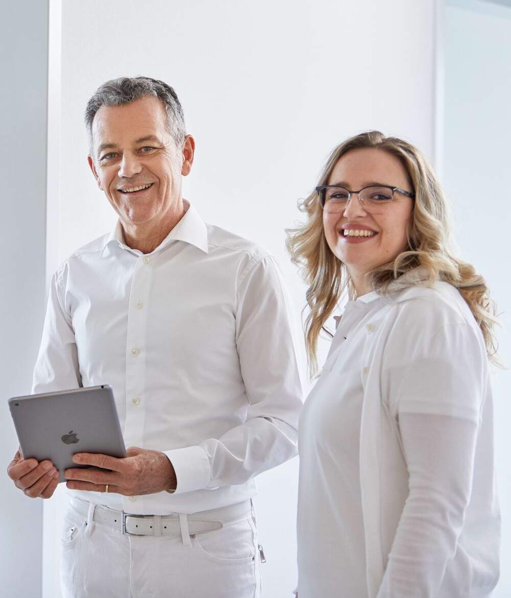 Ein Arzt und eine &Auml;rztin lachen in die Kamera.