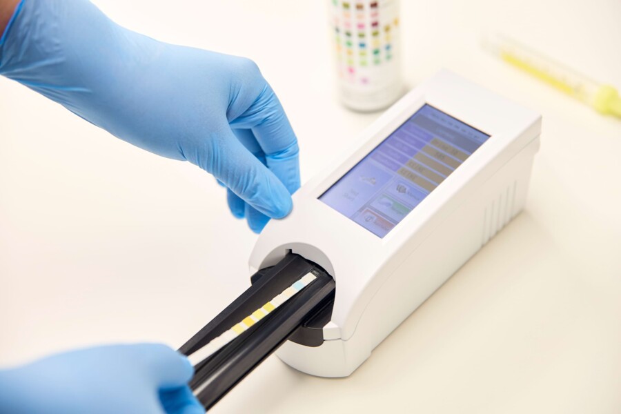 Ein Teststreifen wird in ein Ger&auml;t f&uuml;r Urinuntersuchungen geschoben.