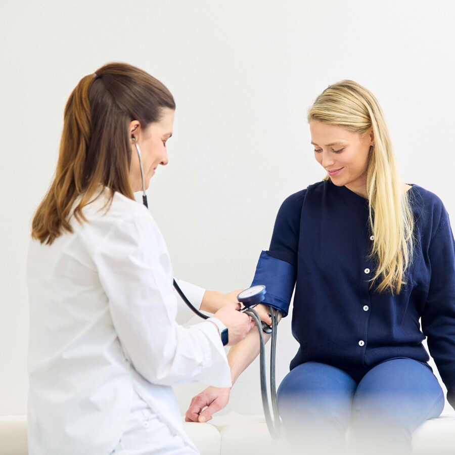 Eine &Auml;rztin misst den Blutdruck einer Patientin.
