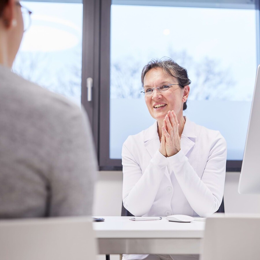 Eine &Auml;rztin ber&auml;t einen Patienten.