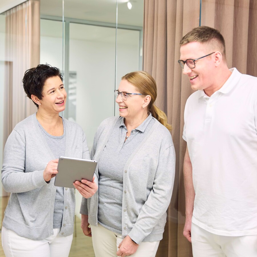 Zwei Mitarbeiterinnen und ein Arzt unterhalten sich.