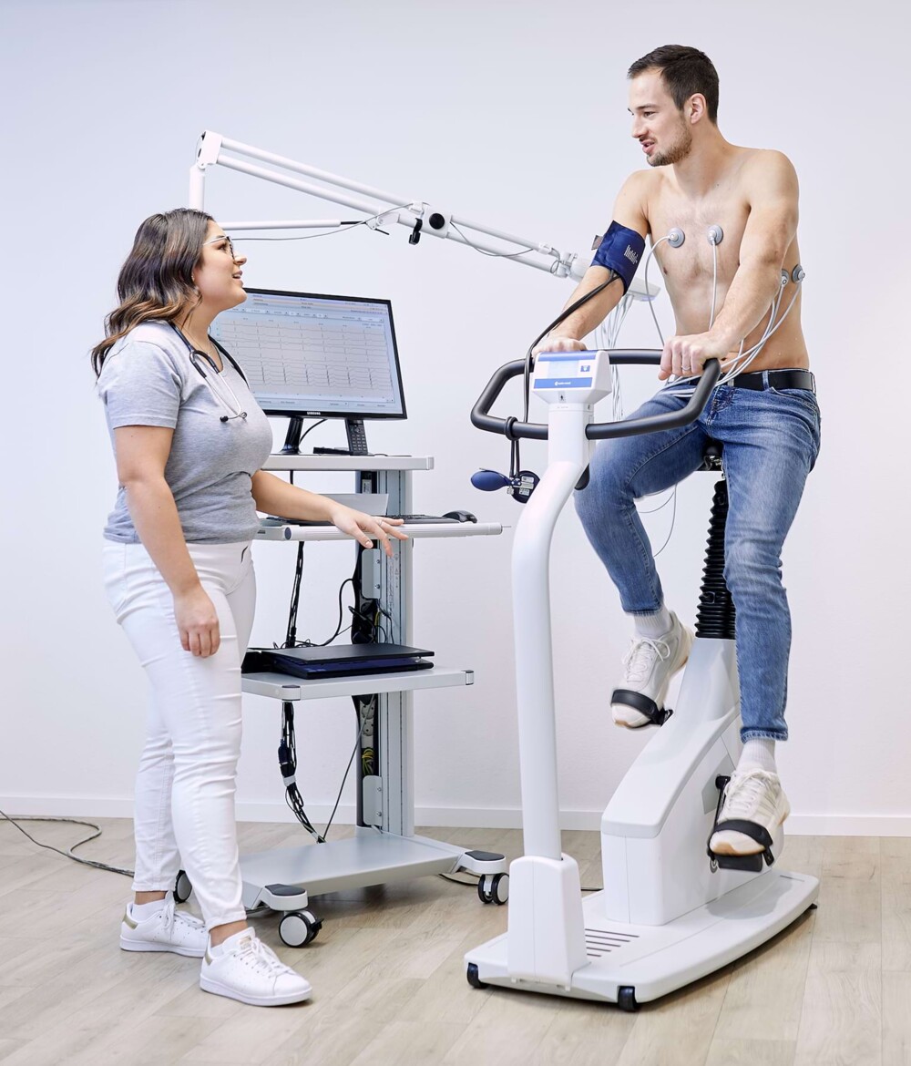 Eine Mitarbeiterin untersucht einen Patienten auf einem Pedal Trainer.