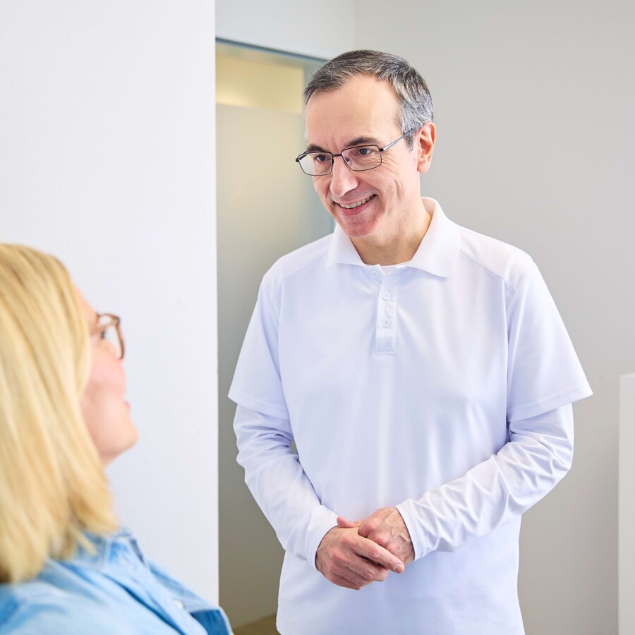 Ein Arzt begr&uuml;&szlig;t eine Patientin im Behandlungsraum.