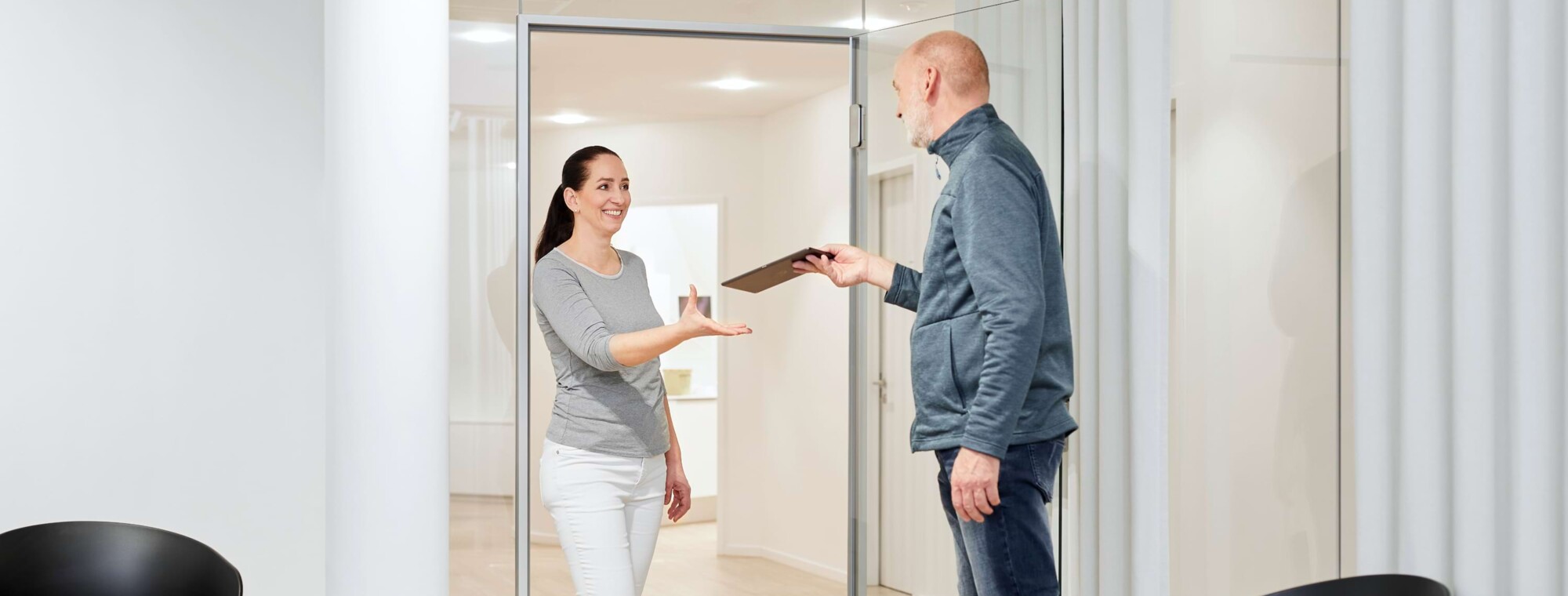 Ein Patient &uuml;berreicht Akten an eine Mitarbeiterin.