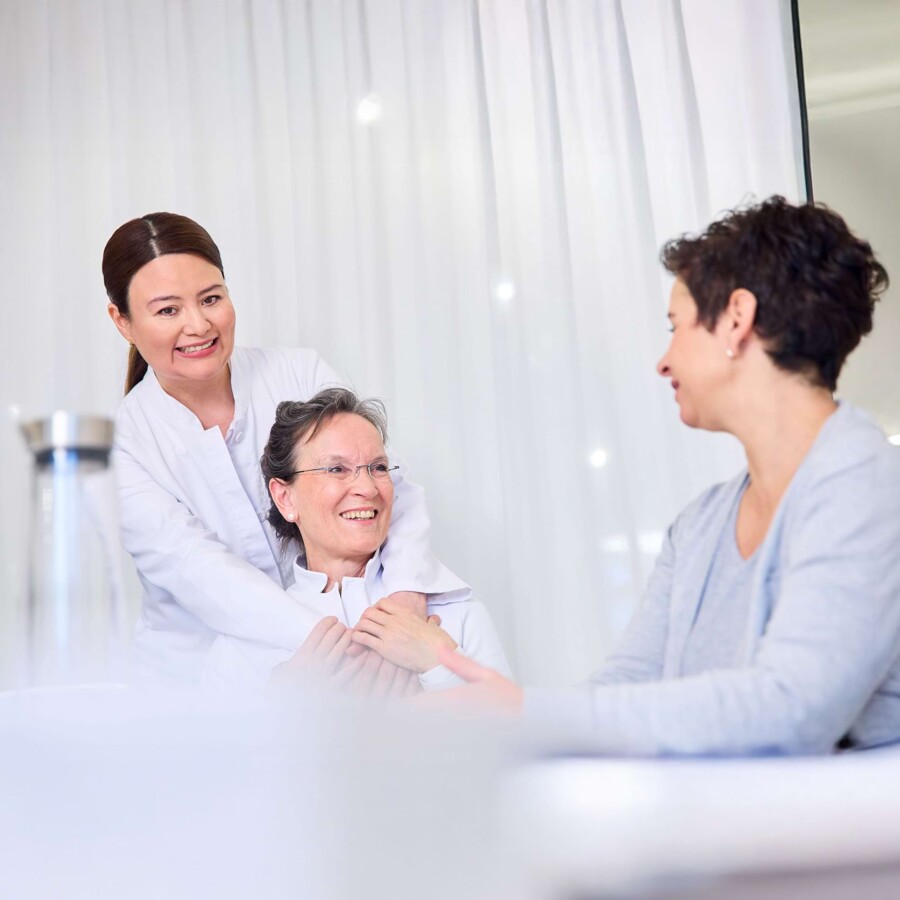 Teambesprechung bei Team Buderer. Drei Mitarbeiterinnen sitzen am Tisch und tauschen sich aus.