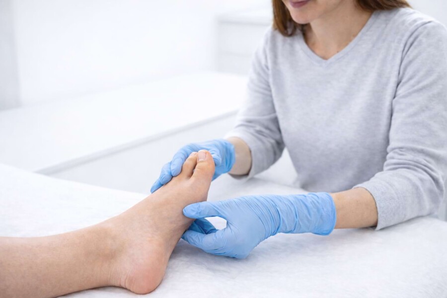 Eine Mitarbeiterin untersucht den Fu&szlig; eines Patienten.