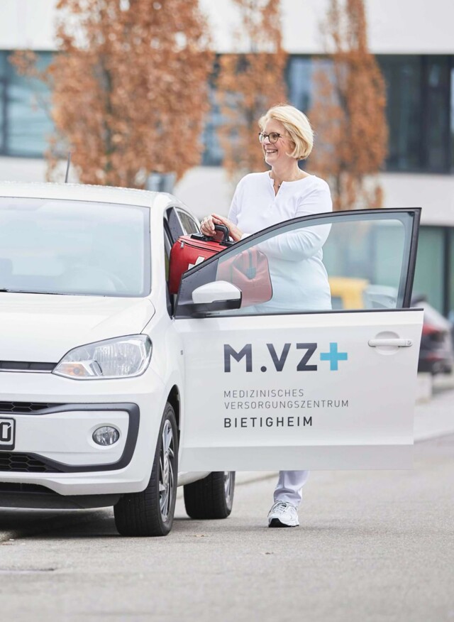 Eine Mitarbeiterin steigt in einen Dienstwagen.