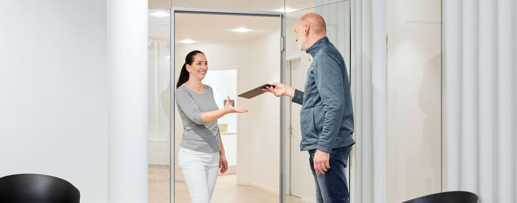 Ein Patient &uuml;berreicht Akten an eine Mitarbeiterin.