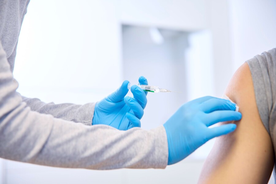 Ein Patient bekommt eine Impfung. Nahaufnahme wie die Spritze an den Arm gef&uuml;hrt wird.