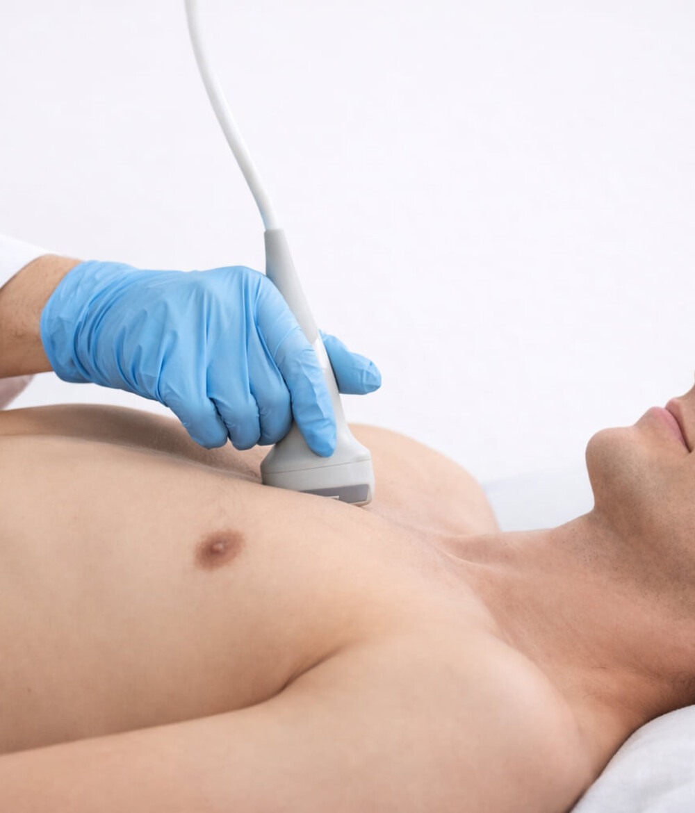 Ein Patient liegt auf einer Behandlungsliege w&auml;hrend eine &Auml;rztin eine Sonografie des Herzens mittels Echokardiografie durchf&uuml;hrt.