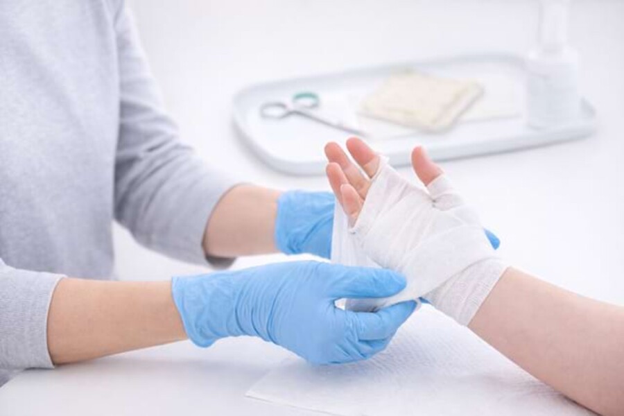 Nahaufnahme wie ein Verband an einer Hand angelegt wird.