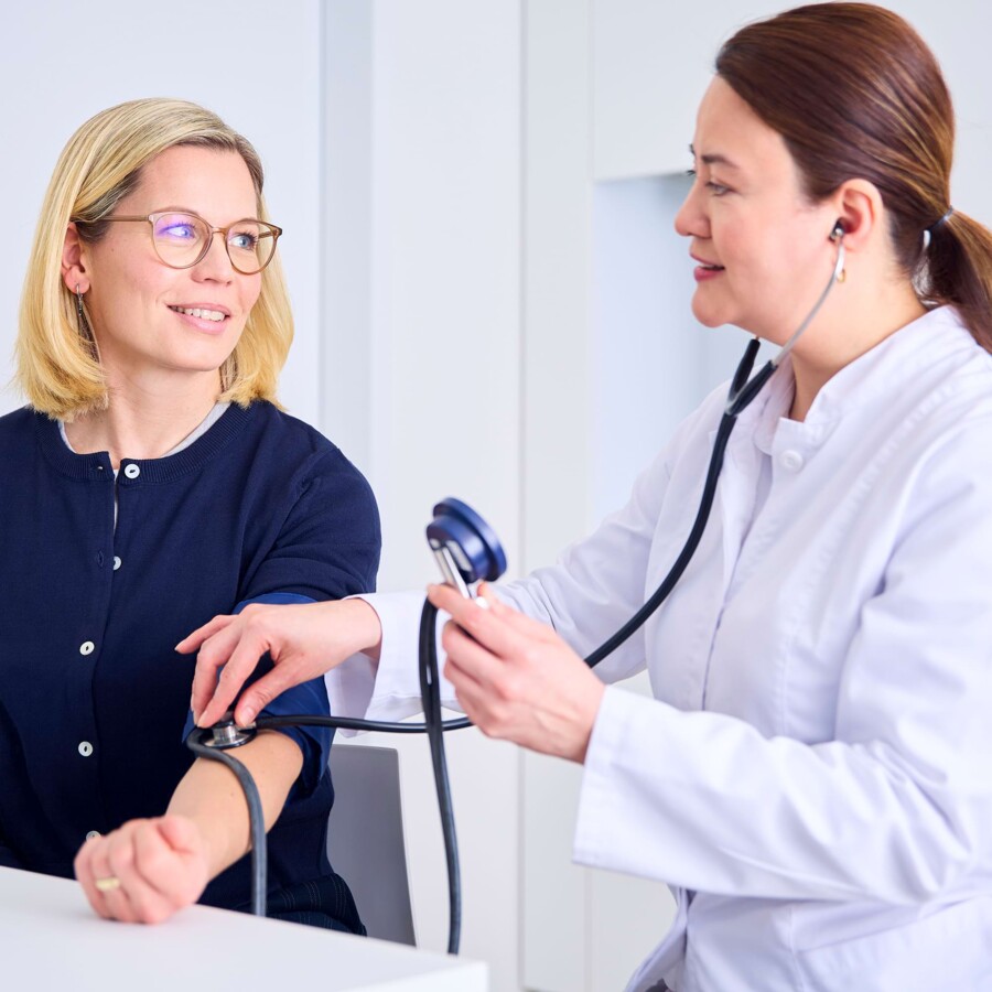 Eine &Auml;rztin misst den Puls einer Patientin.