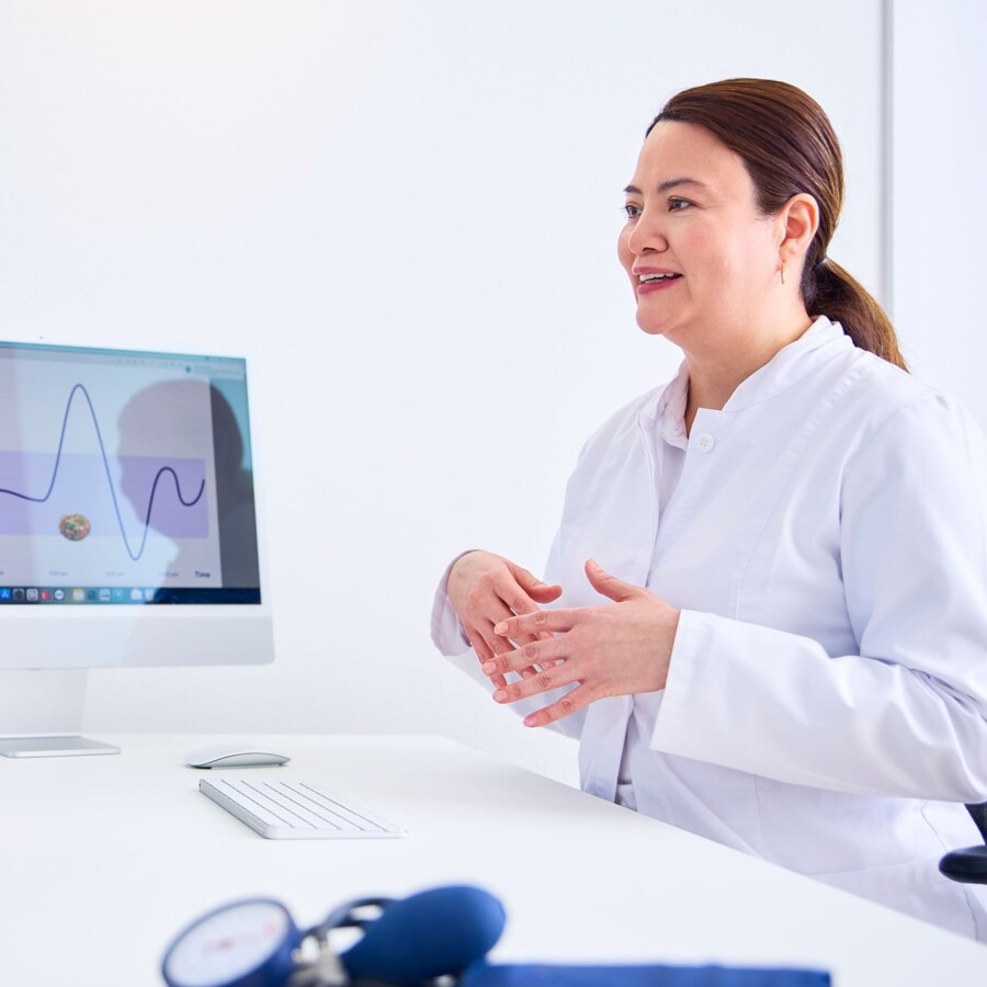 Eine &Auml;rztin erkl&auml;rt etwas im Beratungsgespr&auml;ch. Auf einem Bildschirm ist ein Diagramm zu sehen.