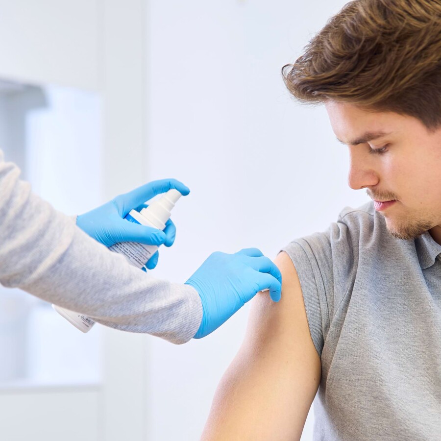 Der Arm eines Patienten wird vor der Impfung desinfiziert.