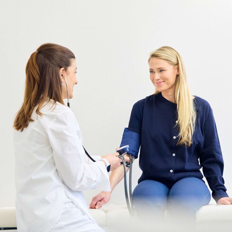 Eine &Auml;rztin untersucht eine l&auml;chelnde Patientin.